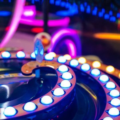 Close-up of a glowing neon arcade game controller with colorful lights and buttons