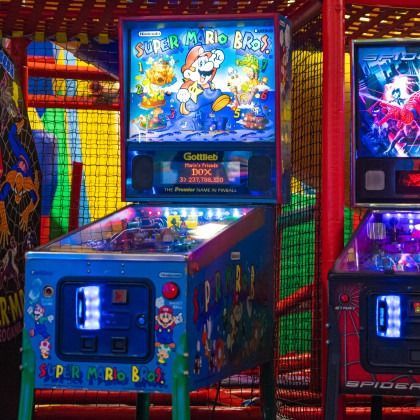Bright Super Mario Bros. arcade cabinet in a colorful arcade, with other game machines nearby