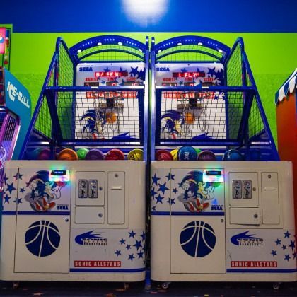 Two blue arcade basketball hoops side by side in a bright arcade game booth