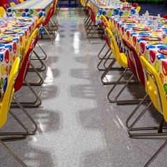 Long tables with colorful tablecloths set for a party in a hall