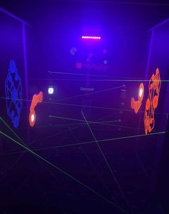 Neon-lit laser tag arena with glowing walls, green laser beams, and orange and blue targets