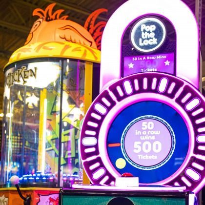 Purple arcade game with glowing circular display next to a chicken-themed prize machine