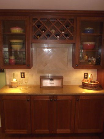Wooden kitchen buffet with cabinets, wine rack, countertops, and lit lamps on both sides