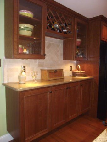 Wooden kitchen buffet with glass cabinets, countertop, wine rack, and under-cabinet lighting