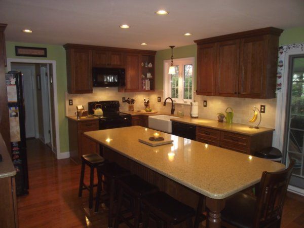 Bright kitchen with dark wood cabinets, large island, beige countertops, and recessed ceiling lights.