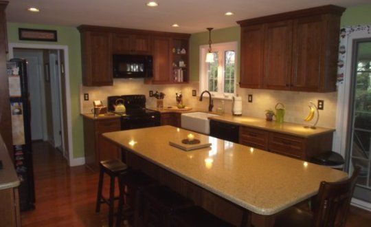 Modern kitchen with dark wood cabinets, beige countertops, and a central island under warm lighting