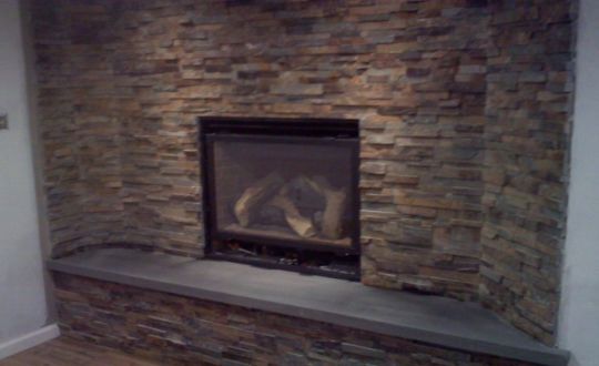 Stone fireplace with a dark mantel and a gray hearth in a living room