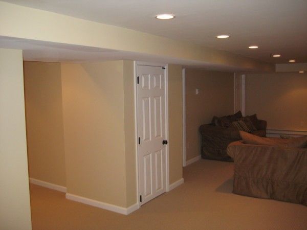 Finished basement with beige walls, white door, carpeted floor, and seating area.