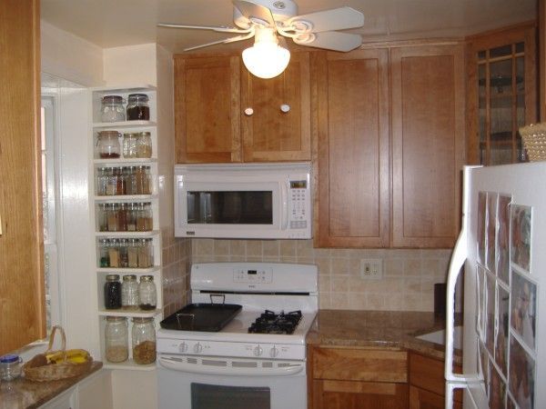 Small kitchen with wooden cabinets, white appliances, tile countertop, and a ceiling fan.