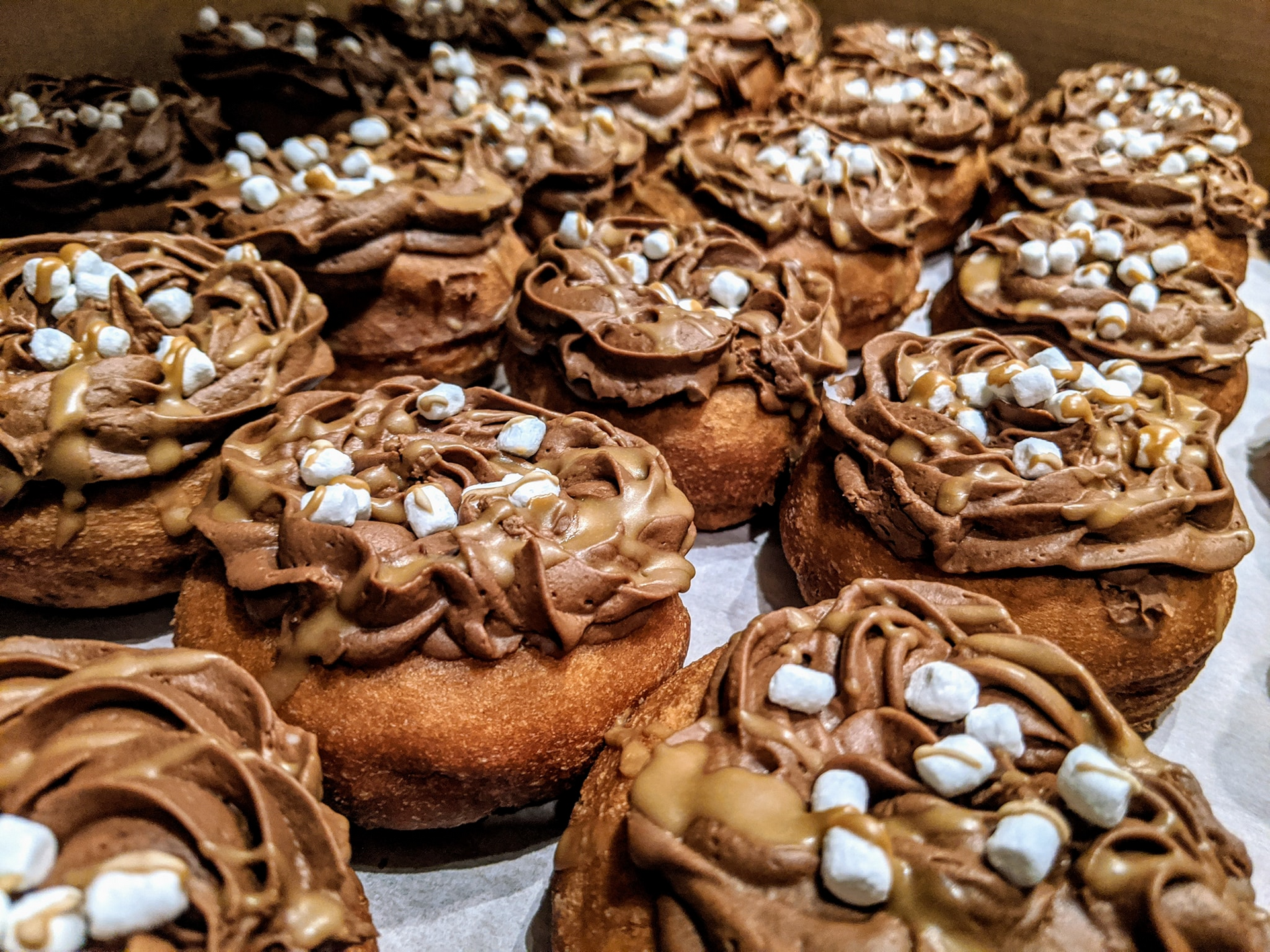 Chocolate frosted donuts topped with marshmallows in a box.