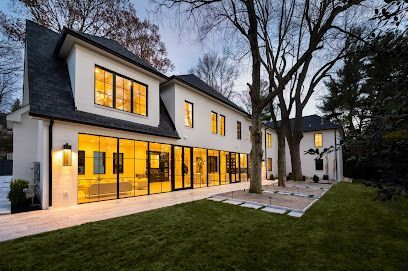 A large white house with a lot of windows and trees in the background.