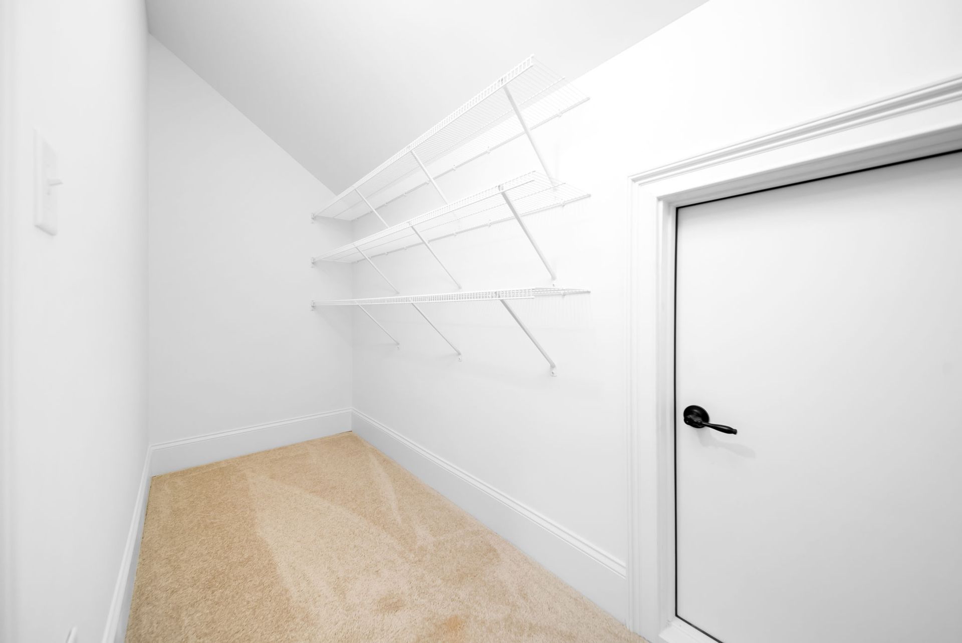 An empty walk in closet with shelves and a door.