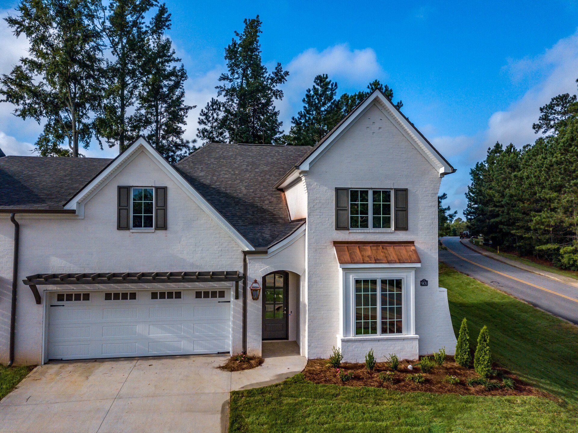 A white house with a garage and a driveway is sitting next to a road.