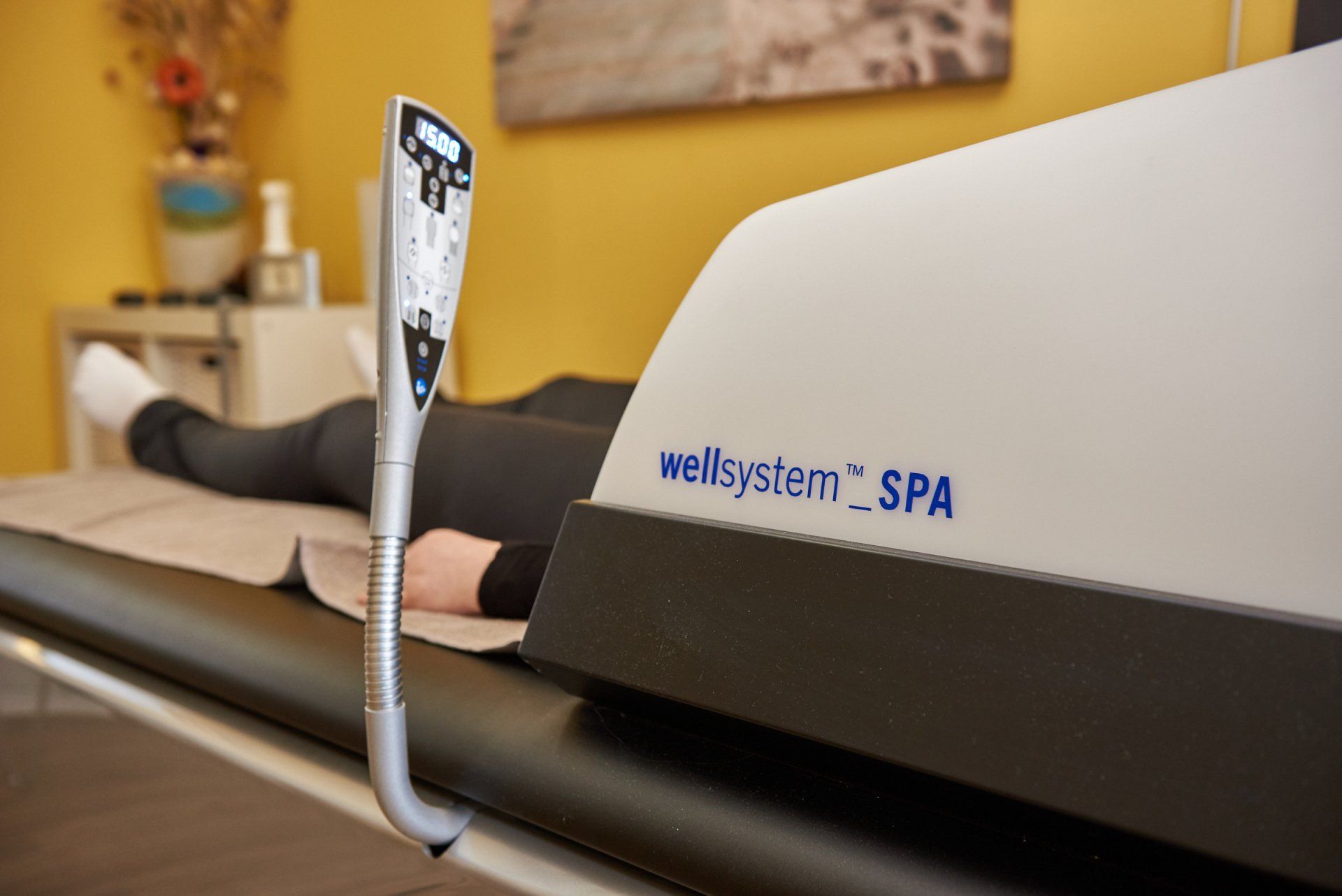Eine Person liegt auf einem Bett neben einer Wellsystem-Spa-Maschine.