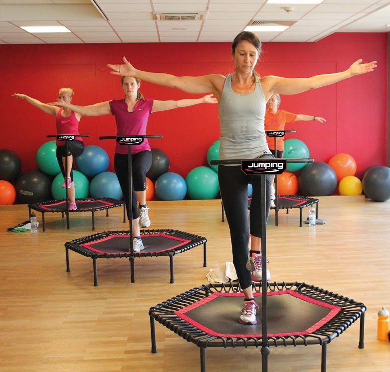 Eine Gruppe von Menschen springt in einem Fitnessstudio auf Trampolinen