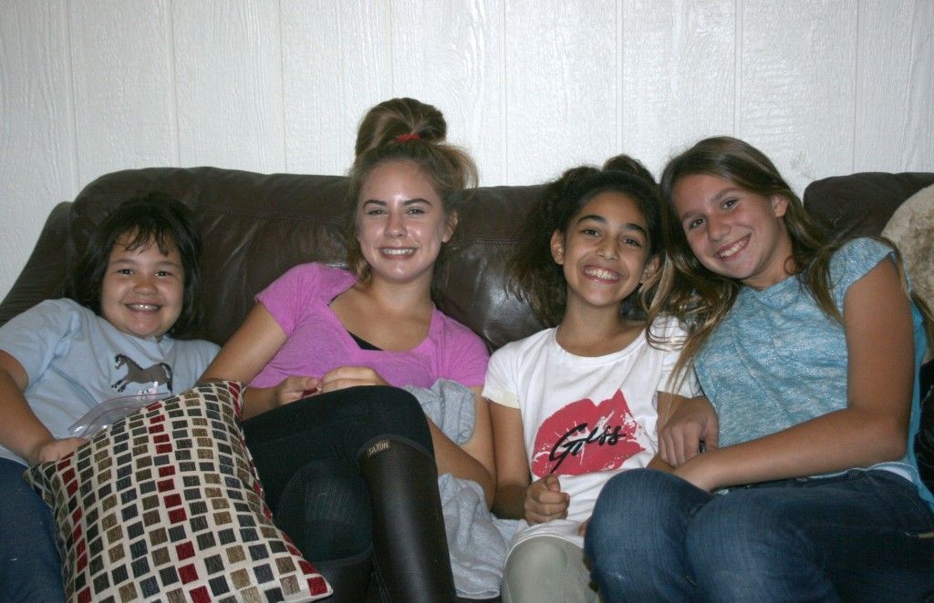 Four girls are sitting on a couch and one of them is wearing a shirt that says girl