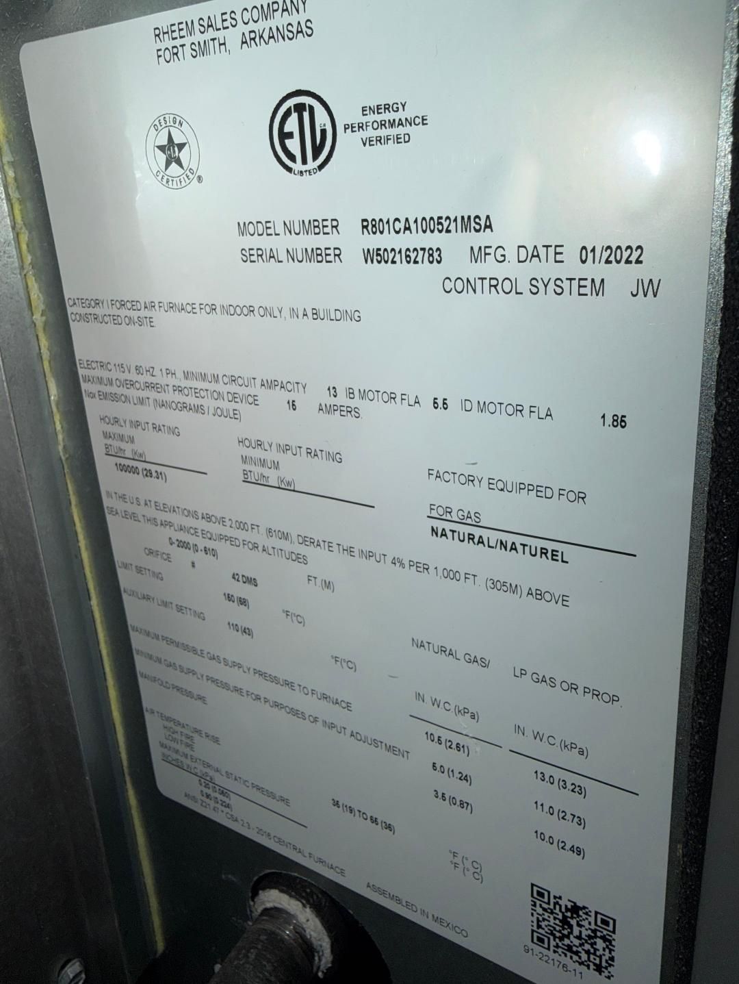 Close-up of a white control panel with printed text, logos, and a small QR code.