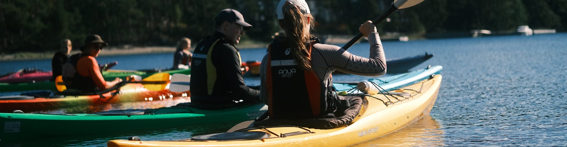 A group of people kayaking on a sunlit lake, paddling in colorful kayaks.