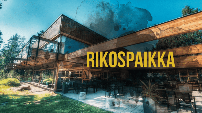 A modern wooden building with a patio and the yellow text "RIKOSPAIKKA" overlaid in the center.