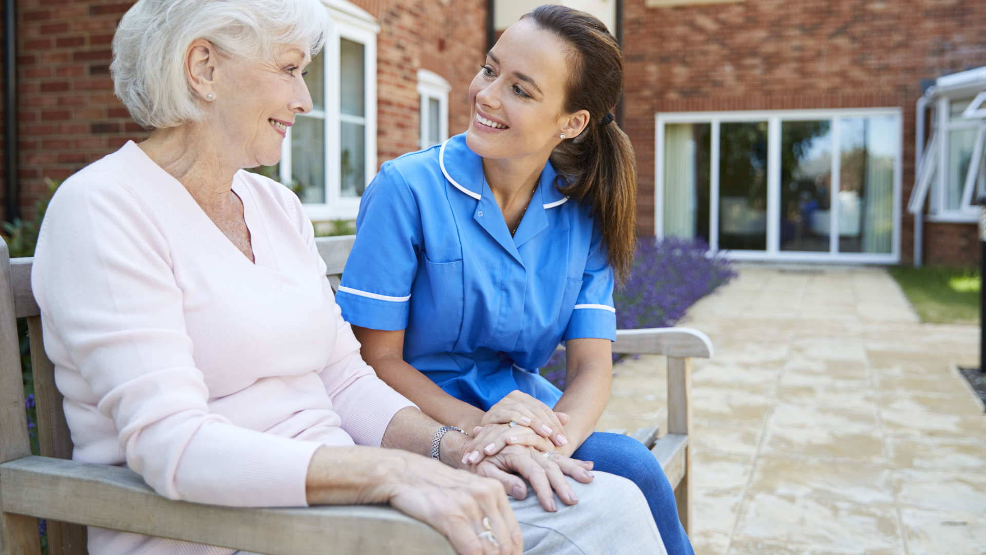 A nurse is sitting on a bench with an elderly woman.