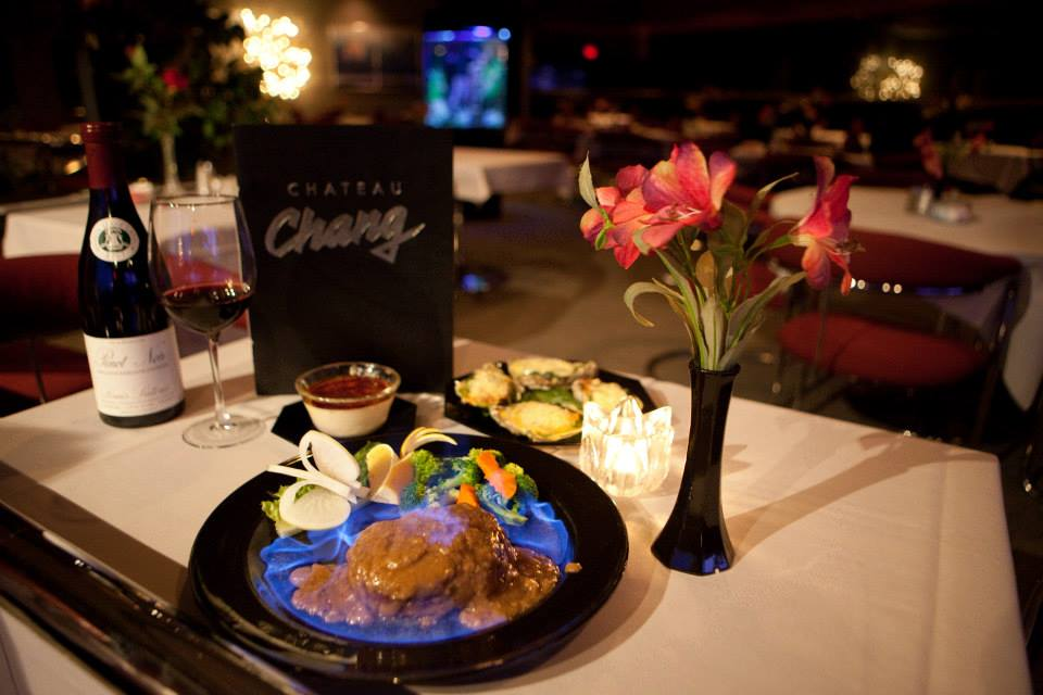 Romantic restaurant table setting with food, wine, flowers, and menu for Chateau Chang.