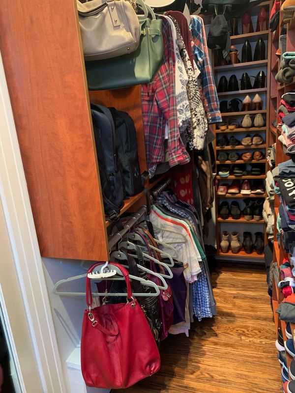 A walk-in closet with hanging clothes, shoes, and handbags in various colors.