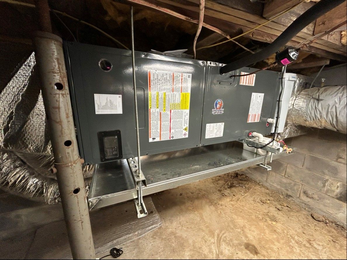 Two outdoor HVAC units beside a house wall beneath two windows at night. Two outdoor HVAC units beside a house wall beneath two windows at night.