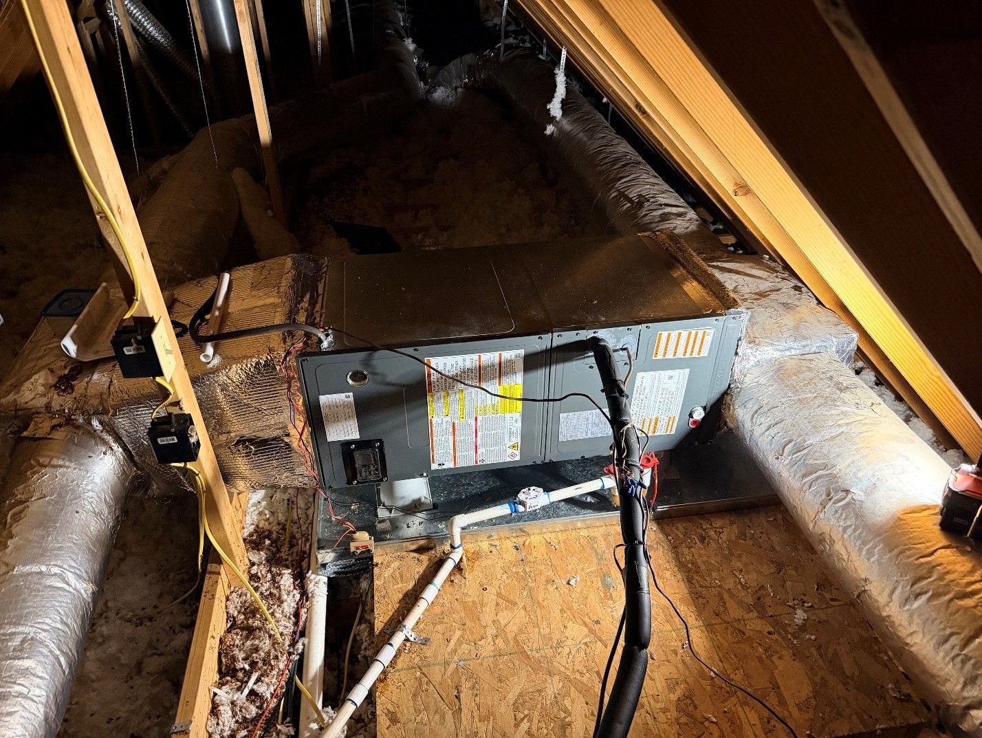 Insulated attic duct with a furnace blower unit and attached cables in a crawlspace