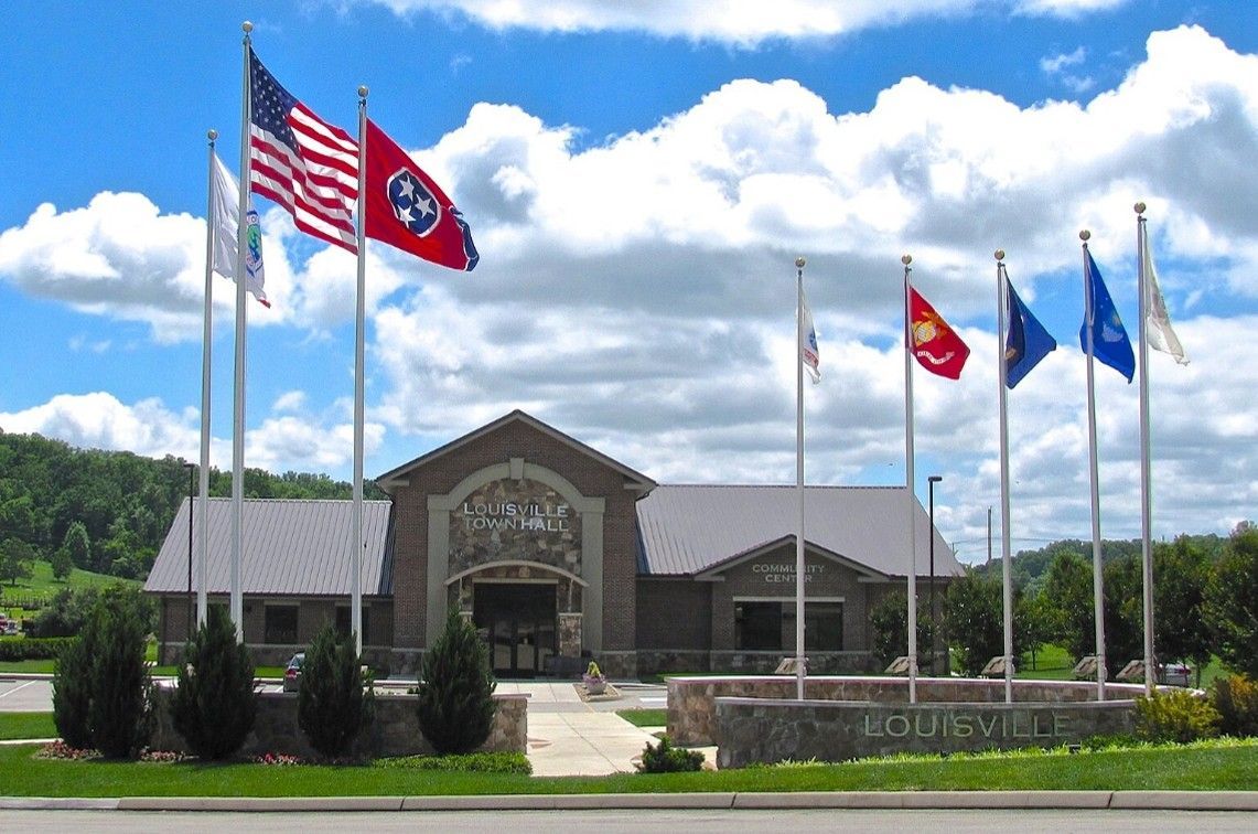 Stone civic building with a row of flags flying in front under a blue sky. Stone civic building with a row of flags flying in front under a blue sky.
