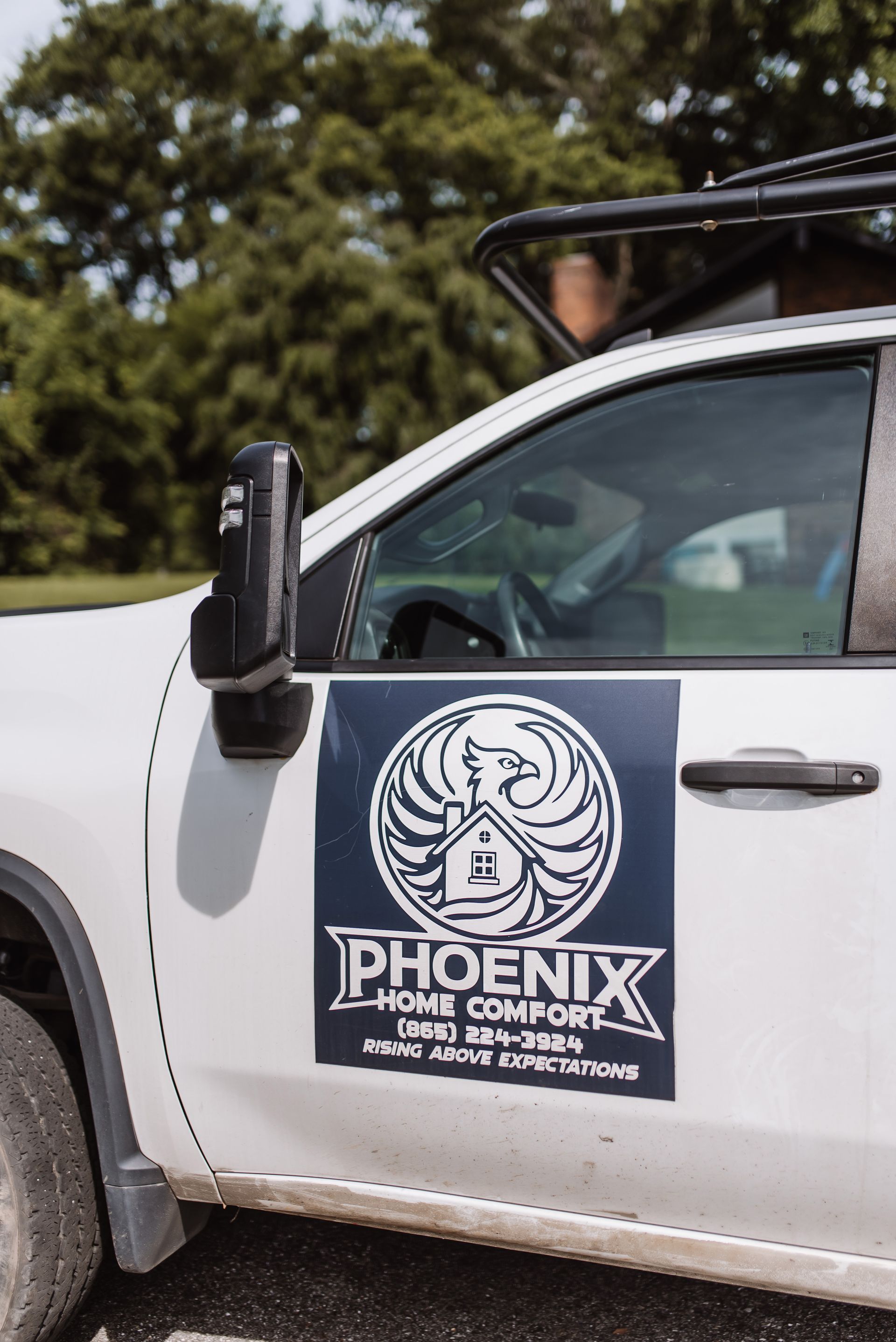 White truck with a PHOENIX logo and text on the door, parked outdoors in daylight