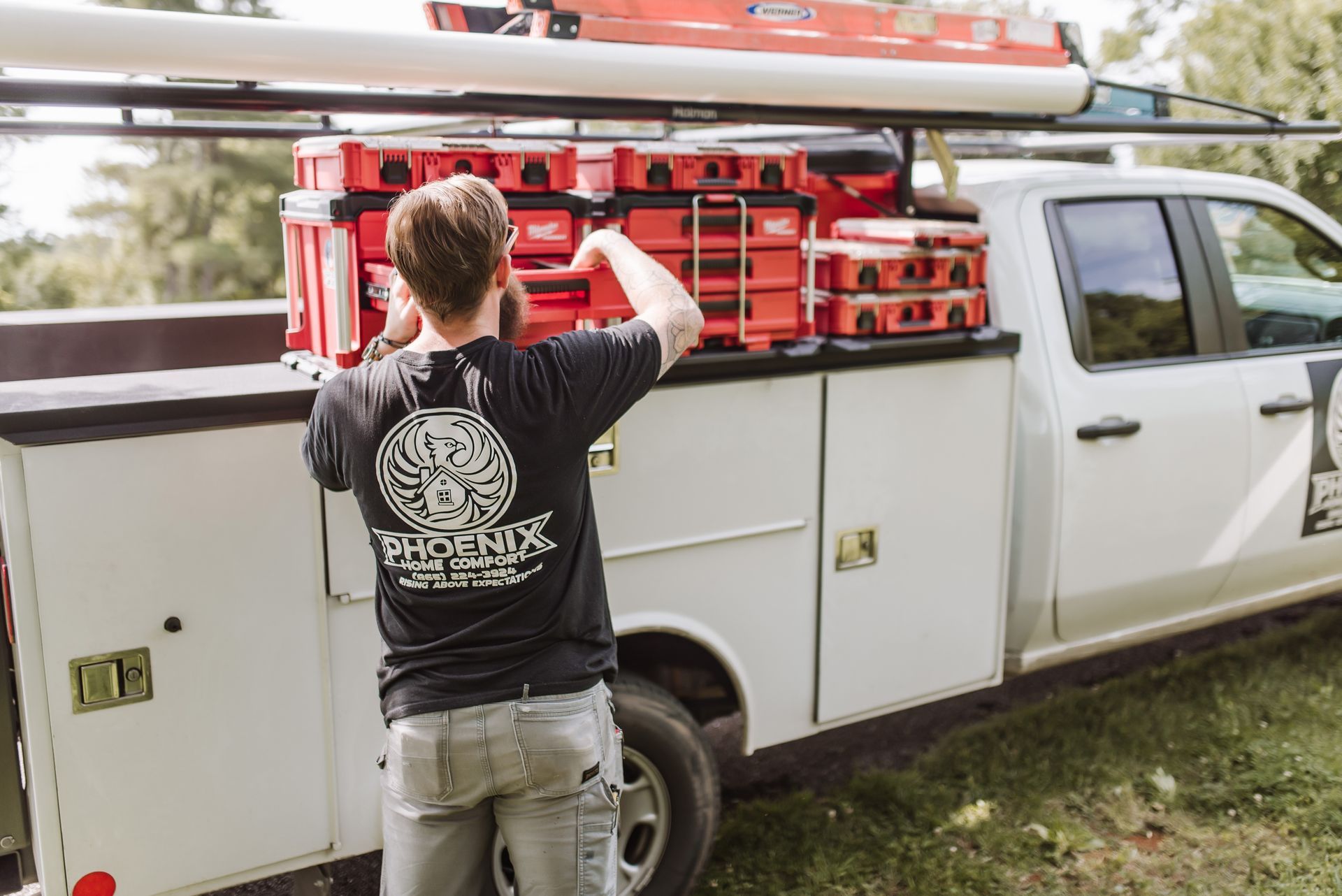 Person loading red equipment onto a white utility truck outdoors