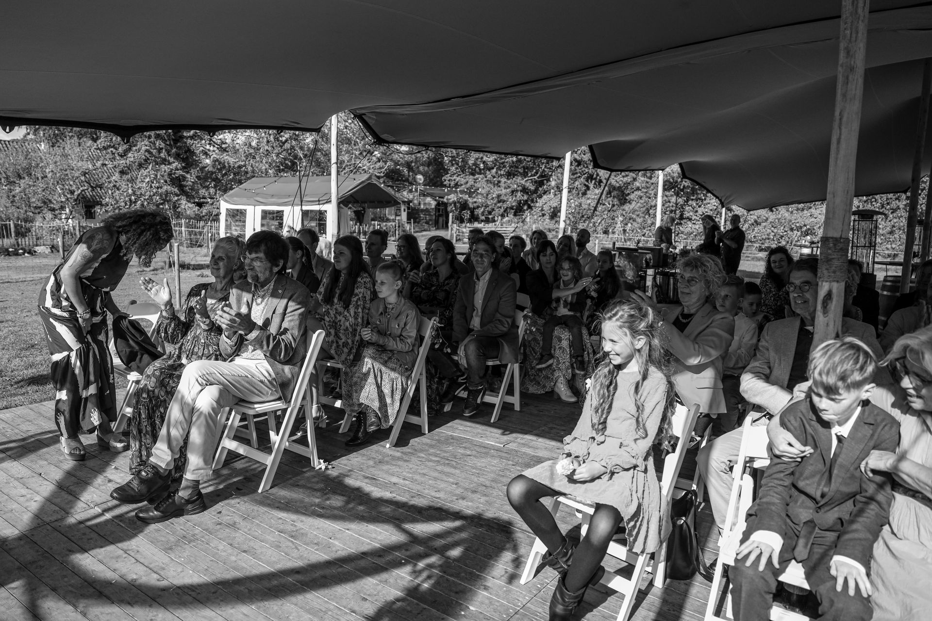Mensen zitten onder een tent tijdens een bijeenkomst in de buitenlucht. Bruiloft fotograaf Heenvliet Geervliet Rockanje