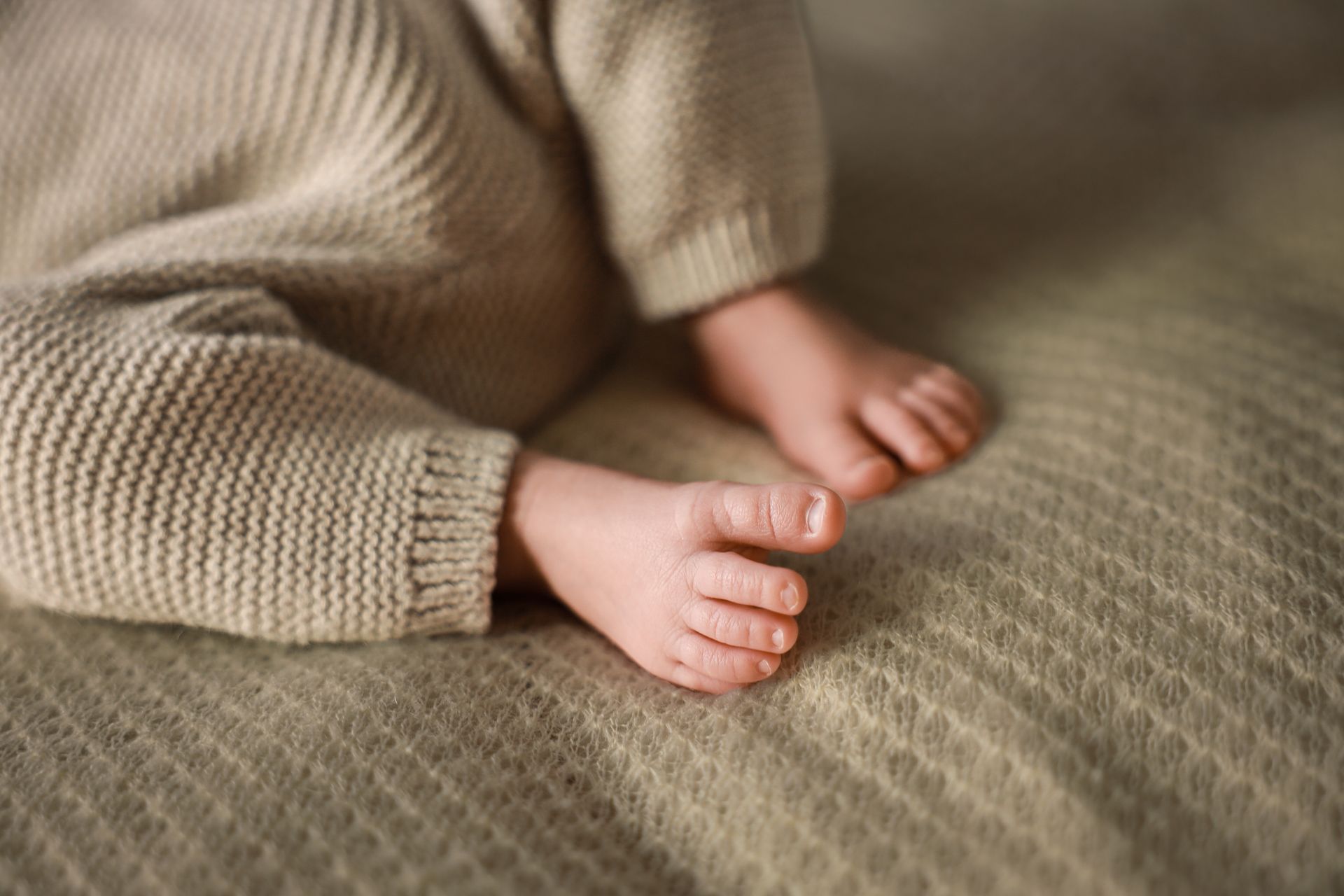 Kleine blote voetjes op een beige gebreide deken. Newborn fotoshoot Zuidland. Newborn fotoshoot Spijkenisse.