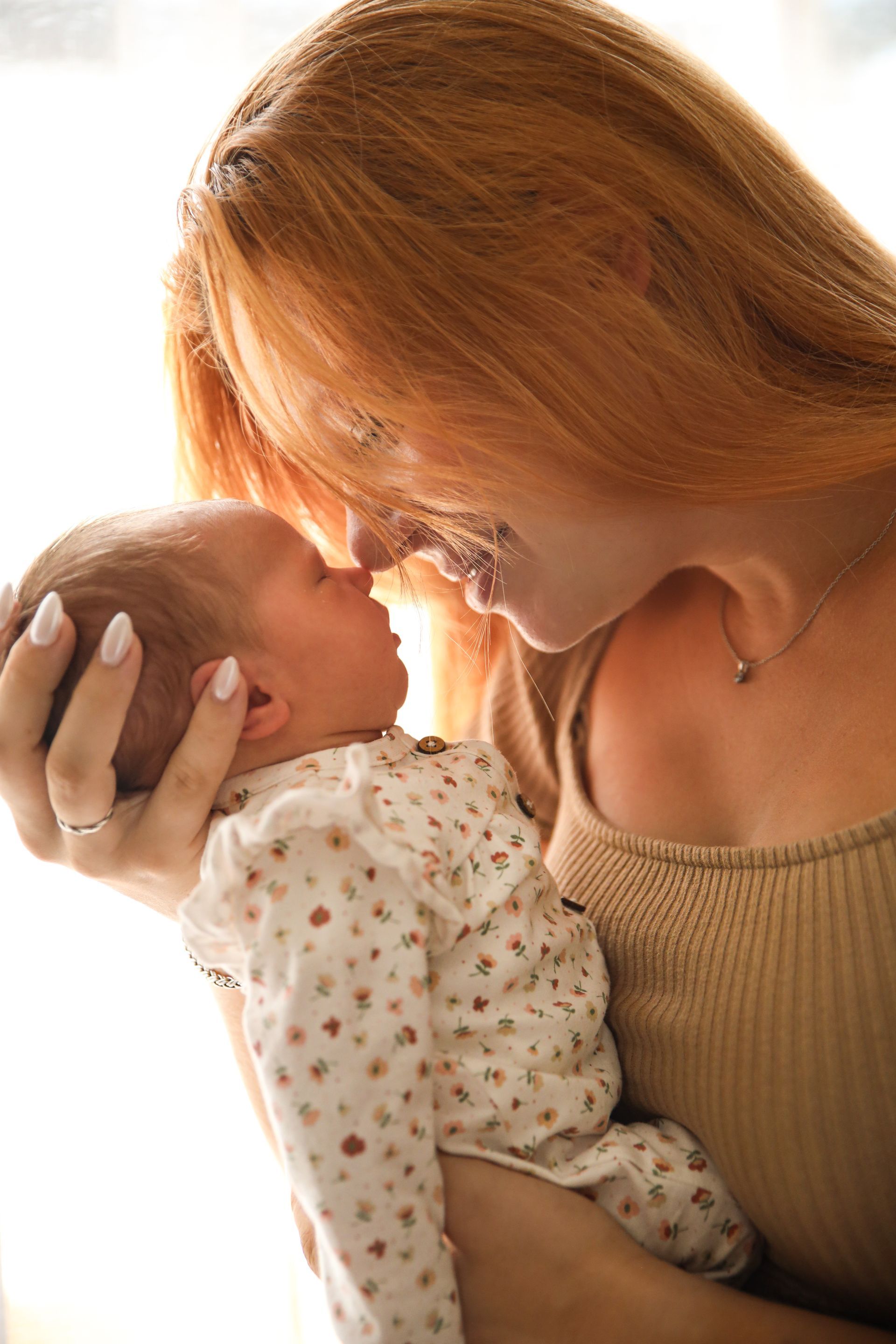 Vrouw houdt een pasgeboren baby teder vast en kust haar. Newborn fotograaf Voorne Putten. Lifestyle newborn fotograaf.