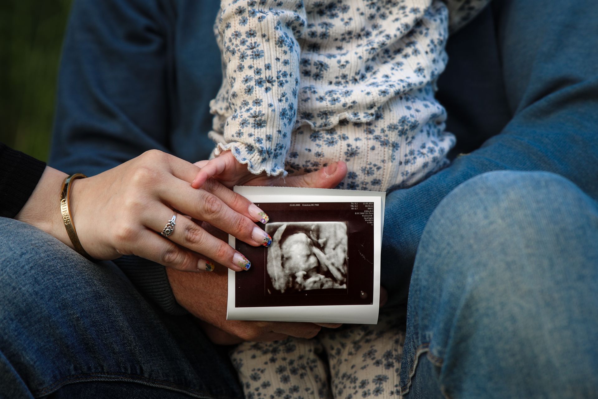 Handen houden een ingelijste echografie vast terwijl ze op een bank zitten. Pregnancy announcement fotoshoot.