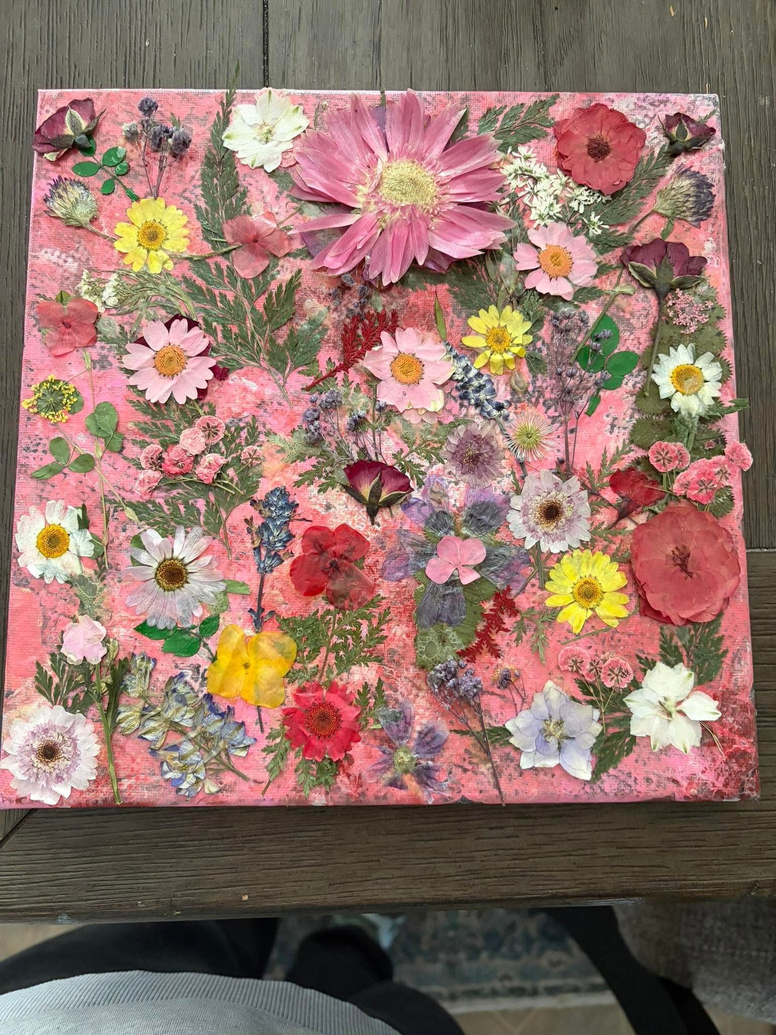 Floral collage with pink background, featuring pressed flowers in pink, yellow, white, and red.
