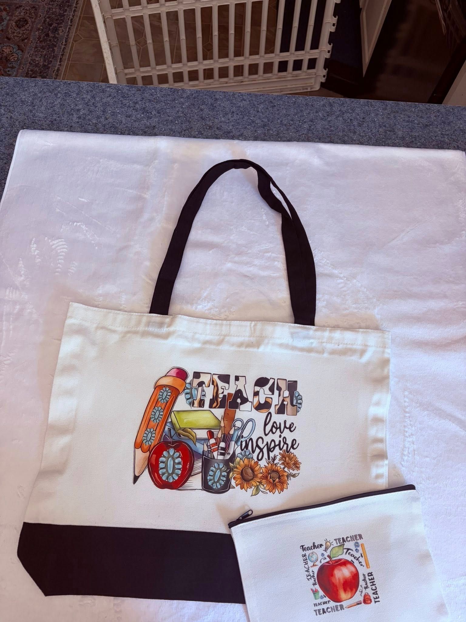White tote bag with black handles and colorful apple-themed embroidery on a table.