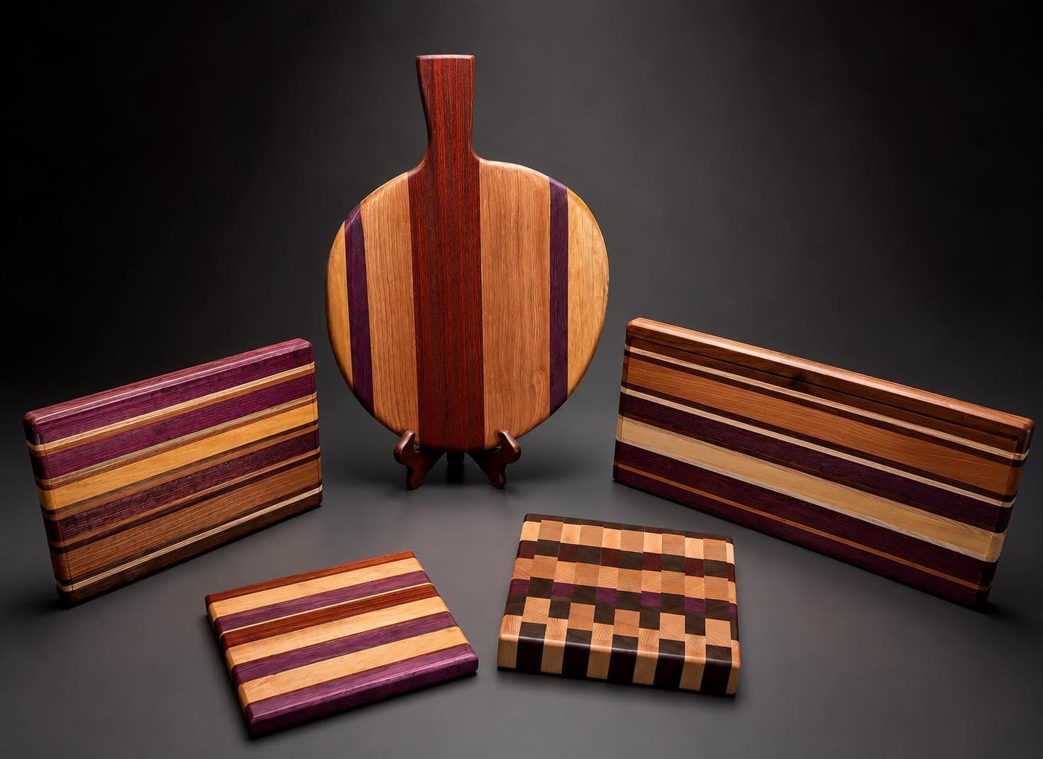 Wooden cutting boards with striped inlay patterns displayed on a dark background