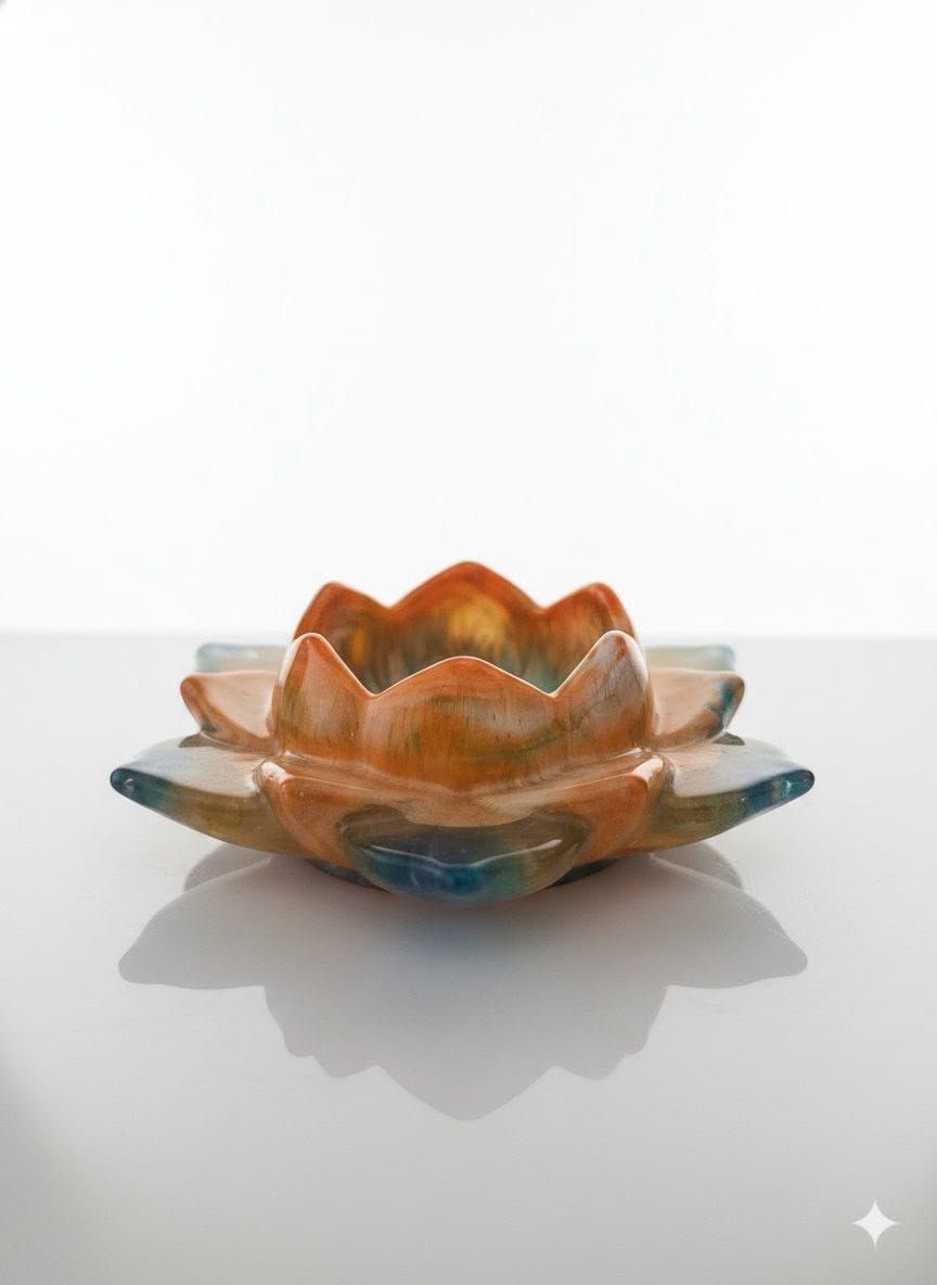 Orange glass lotus-shaped bowl on a white surface, with a soft shadow.