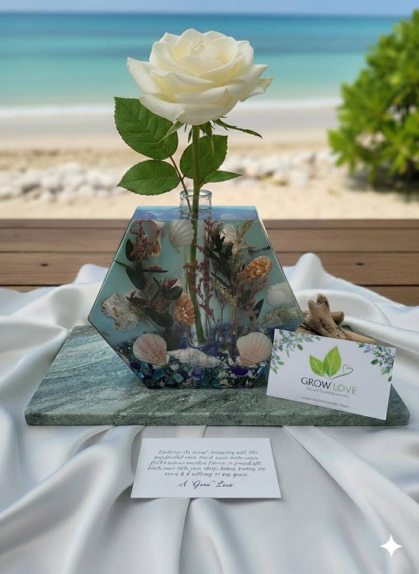 White rose in a glass vase on a beach table with seashells, ocean and sand in the background