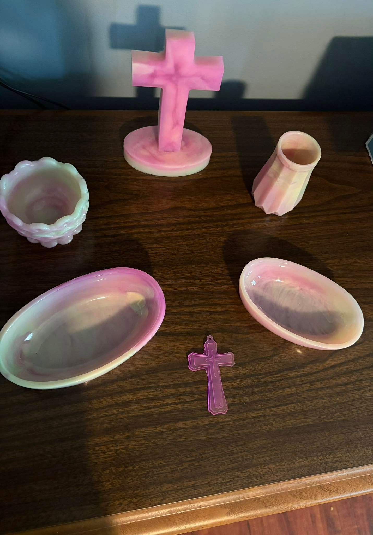 Pink altar set with cross, chalice, candle holder, plates, and small cross on a wooden table