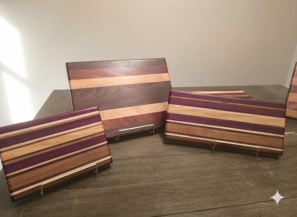 Three striped wooden cutting boards displayed on a dark table in a bright room