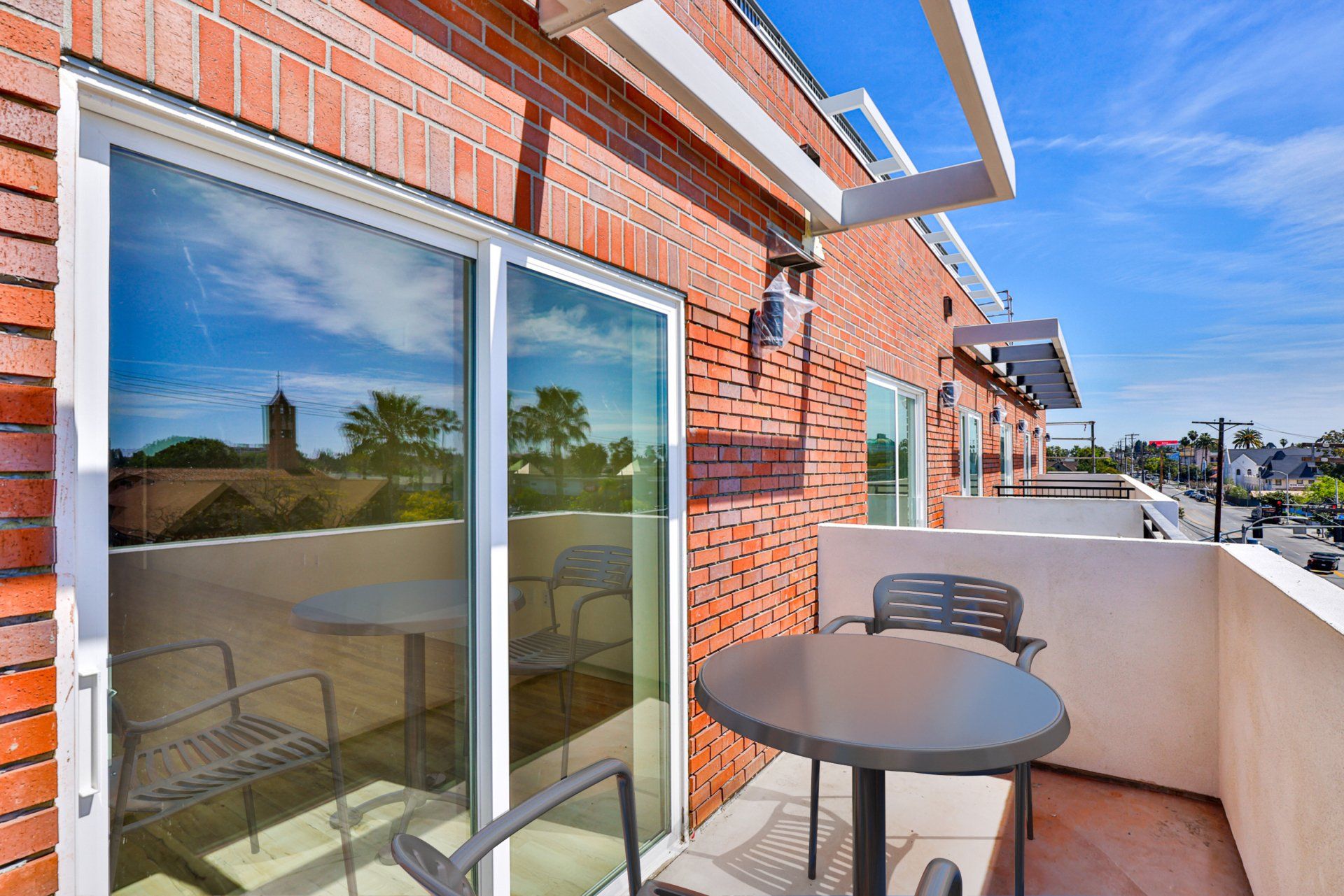 A balcony with a table and chairs in front of a brick building.