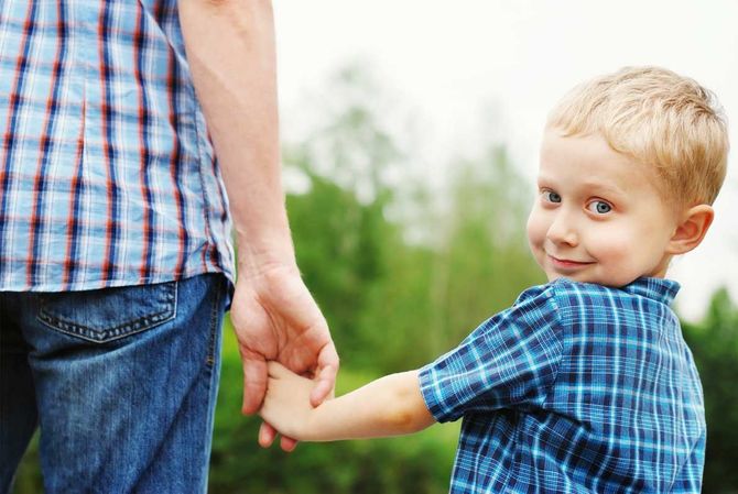 A child is holding a man's hand
