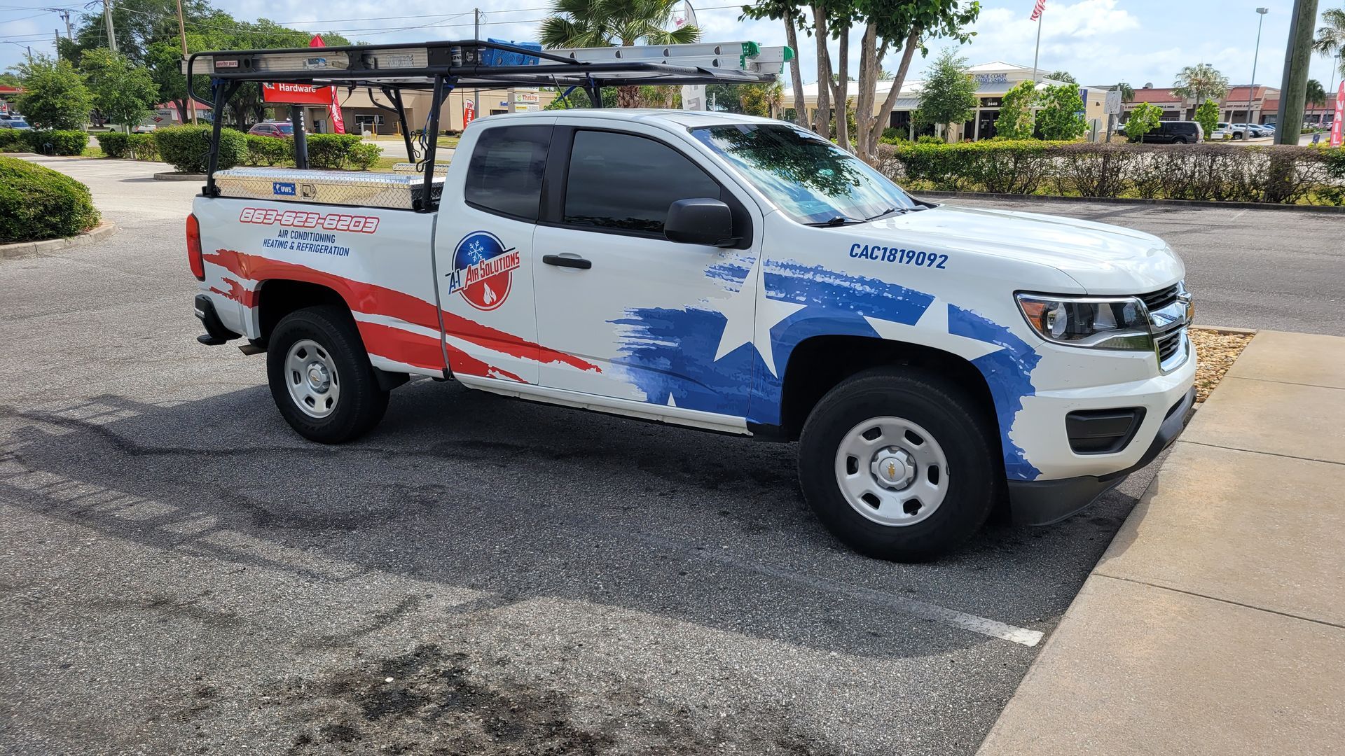 White pickup truck with American flag design parked in front of a business.