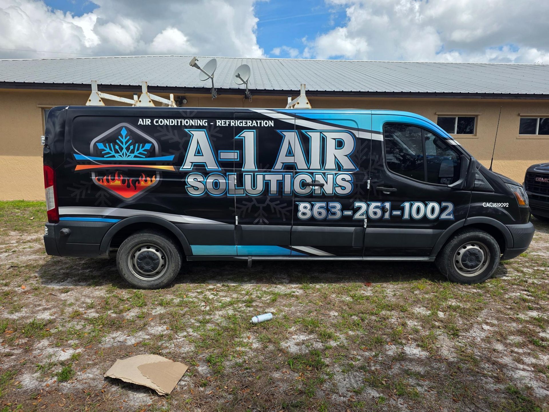 Black A-Lair Solutions van parked outdoors with company logo, website, and phone number on the side