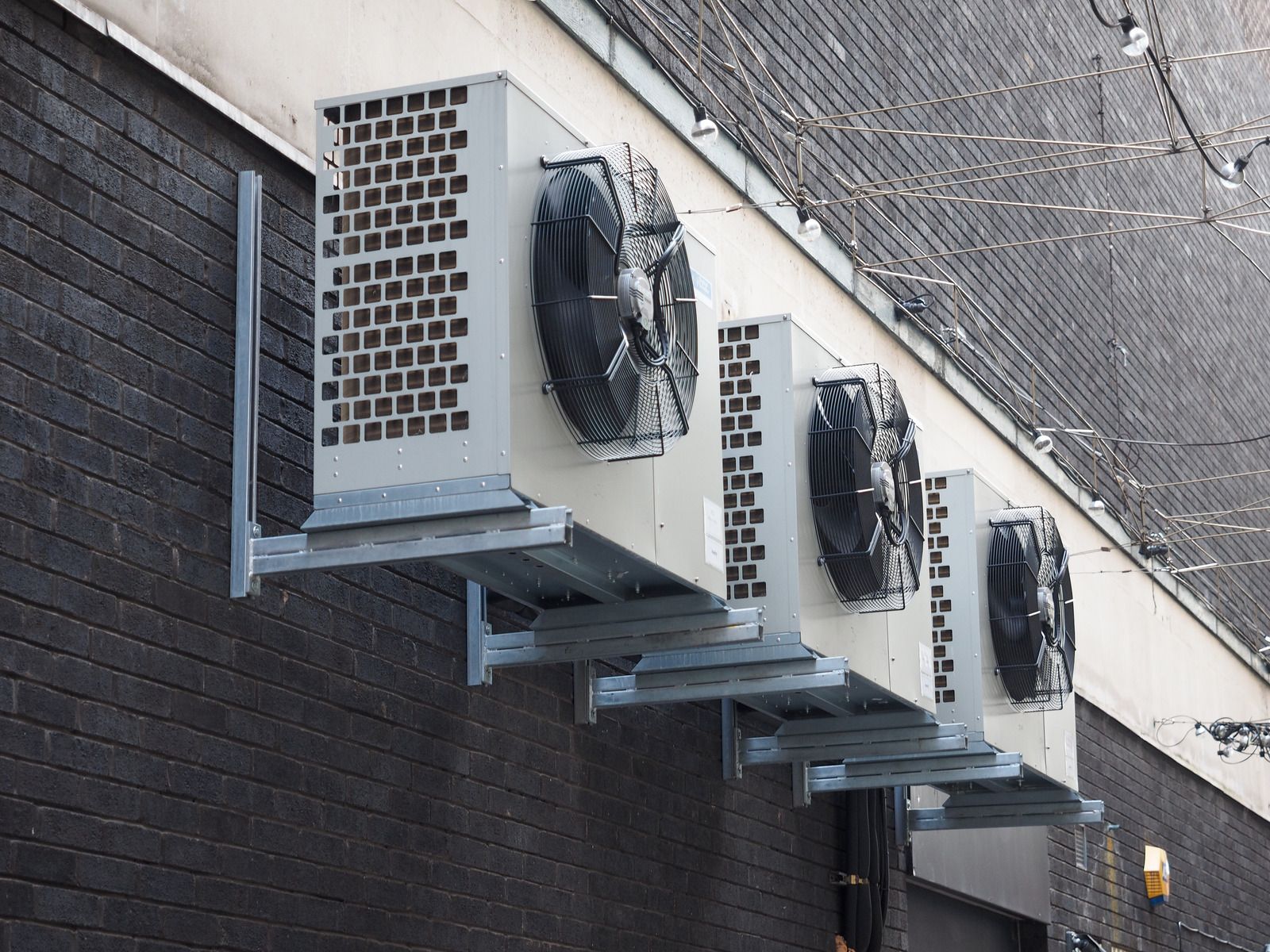 Four outdoor AC units mounted on a brick wall.