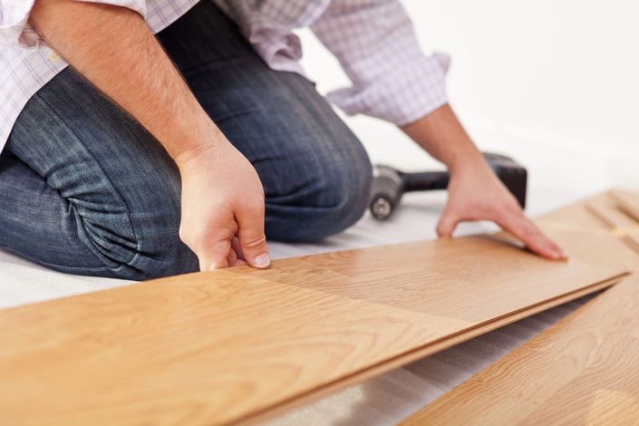 Persona che posa una tavola di legno per il pavimento durante l'installazione in casa.
