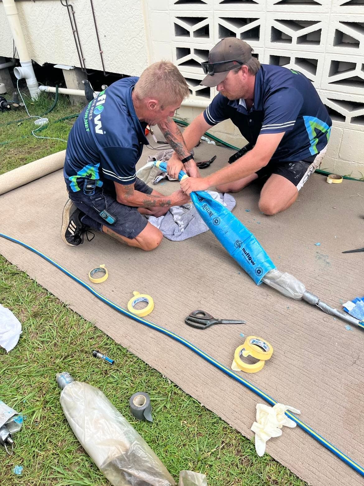 Two Men Working on A Pipe Outdoors — Nuflow Wide Bay in Hervey Bay, QLD