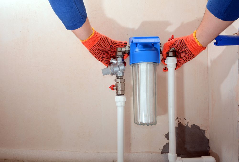A Person Installing a Water Filter on Pipes in A Room — Nuflow Wide Bay in Bargara, QLD